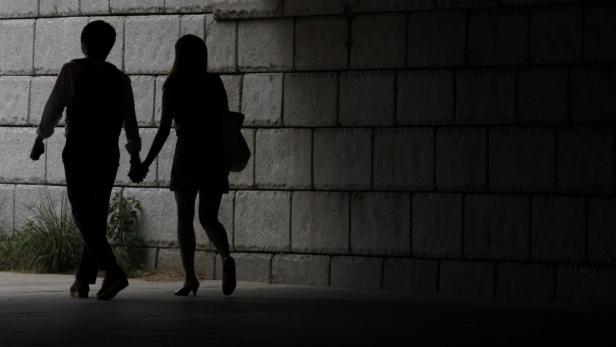 A young couple walks while holding hands under a b