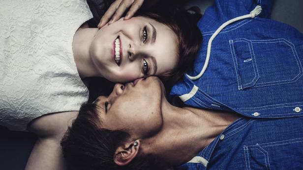 Ein Paar liegt eng umschlungen, die Frau lächelt in die Kamera.