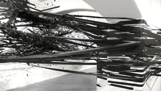 Eine Installation aus schwarzen Bändern und Linien in einem weißen Raum.
