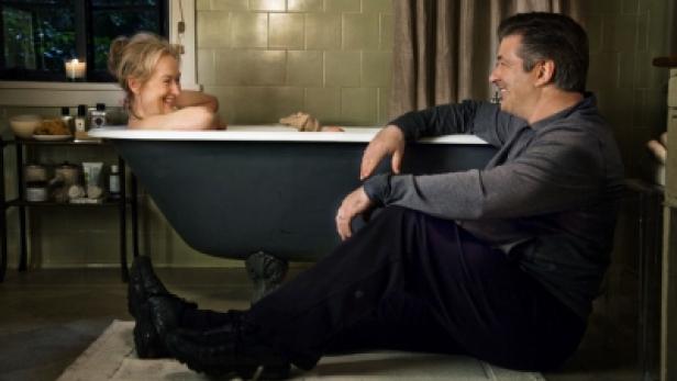 Meryl Streep liegt in einer Badewanne, während Alec Baldwin daneben sitzt und sie anlächelt.