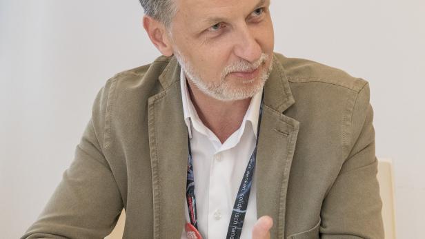 Roman Hebenstreit sitzt an einem Tisch und gestikuliert.