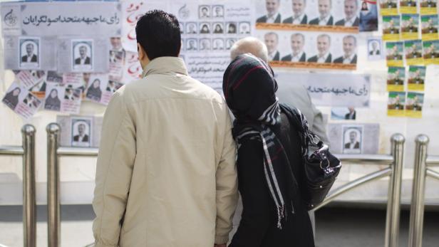 EDITORS&#039; NOTE: Reuters and other foreign media are subject to Iranian restrictions on leaving the office to report, film or take pictures in Tehran. A couple looks at electoral posters at the corner of a square in northern Tehran February 29, 2012. Iranians will vote on Friday in a parliamentary election that is a contest between loyalists to Supreme Leader Ayatollah Ali Khamenei and allies of President Mahmoud Ahmadinejad. REUTERS/Morteza Nikoubazl (IRAN - Tags: POLITICS ELECTIONS)