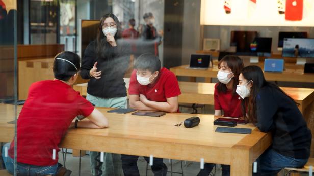 People wear face masks as they listen to a presentation in an Apple Store in the Sanlitun shopping district in Beijing