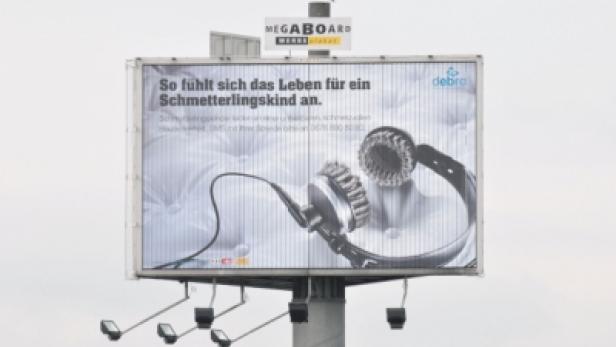 Eine Werbetafel zeigt Kopfhörer und den Slogan „So fühlt sich das Leben für ein Schmetterlingskind an.“.