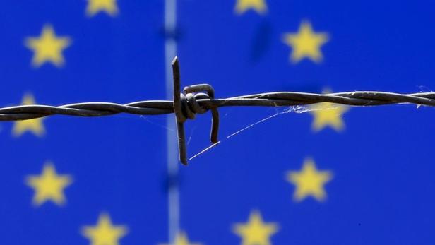 Stacheldraht vor der Flagge der Europäischen Union.