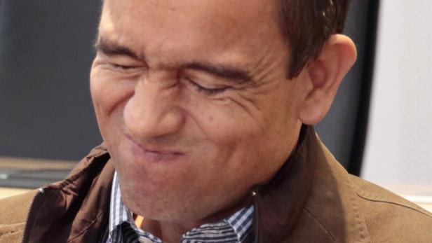 Ein Mann verzieht sein Gesicht zu einer Grimasse.