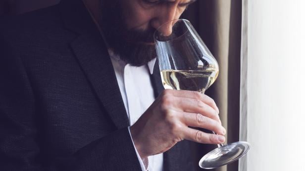 Ein Mann kostet Weißwein aus einem Weinglas