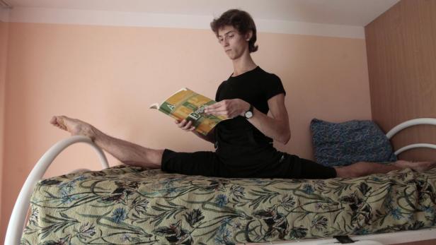 RNPS IMAGES OF THE YEAR 2012 - Yuri Kudryavtsev, 18, student of the Krasnoyarsk choreographic college, does leg-splits while reading a book in the Siberian city of Krasnoyarsk, October 4, 2012. Kudryavtsev, accompanied by his fellow student, Marina Volkova, 16, prepared before taking part in a professional one-week-long ballet contest, dedicated to the 85th anniversary of a well-known Russian choreographer Yuri Grigorovich, along with actors from opera and ballet theatres and graduates of choreographic colleges from different Russian cities. Kudryavtsev and Volkova are winners of the 2011 Grand Prix of the St.-Petersburg&#039;s Mikhailovsky Theatre all-Russian ballet schools competition. REUTERS/Ilya Naymushin (RUSSIA - Tags: SOCIETY)