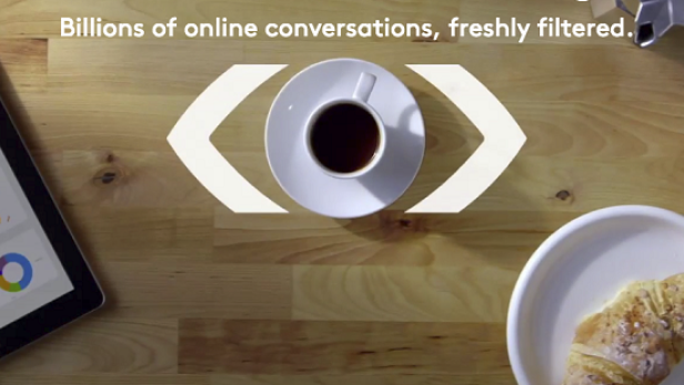 Ein Tablet mit Diagrammen, eine Tasse Kaffee und ein Croissant auf einem Holztisch.