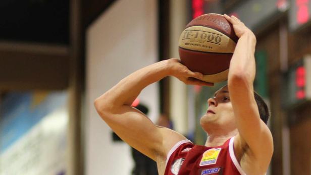 Ein Basketballspieler zielt mit einem Ball vom Typ Spalding auf den Korb.