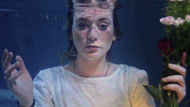 Eine Frau hält einen Blumenstrauß unter Wasser.