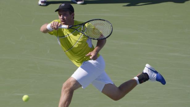 Ein Tennisspieler schlägt einen Ball auf einem Tennisplatz.