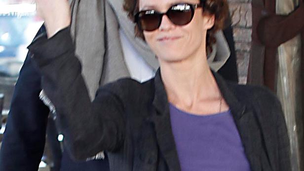 Vanessa Paradis mit erhobenem Victory-Zeichen, im Hintergrund ein Mann mit Bart und Sonnenbrille.