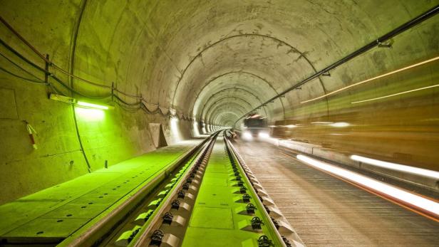 Ein Tunnel mit Gleisen und einem Fahrzeug am Ende, das Lichtspuren hinterlässt.