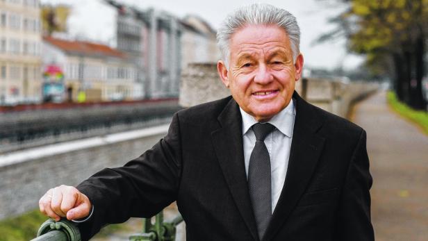 Ein älterer Mann im Anzug lächelt in die Kamera.