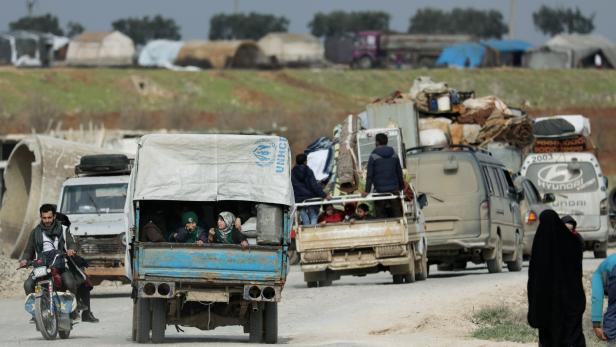 Internally displaced people ride on trucks with their belongings in Afrin