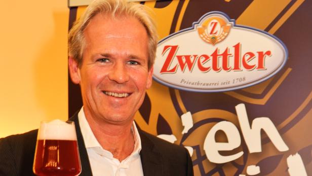 Ein Mann mit einem Glas Zwettler Bier vor einem Zwettler-Logo.