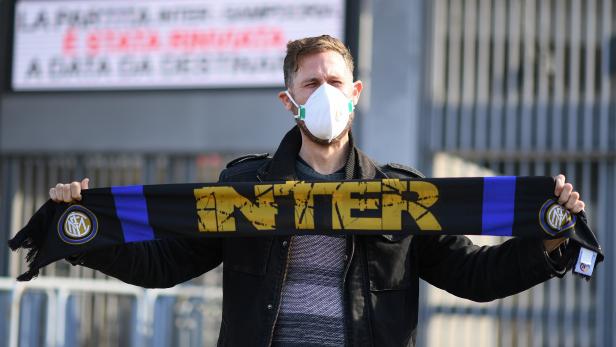 A man wearing a face mask stands outside the San Siro stadium after the Inter Milan v Sampdoria Serie A match was cancelled due to an outbreak of the coronavirus in Lombardy and Veneto, in Milan