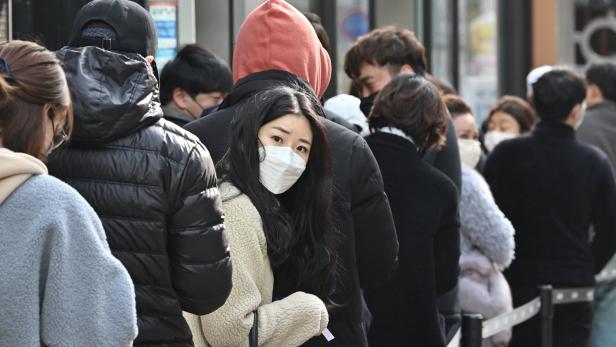 Eine Frau geht mit einer Gesichtsschutzmaske Ende Februar in einem Wohngebiet in Shanghai spazieren.