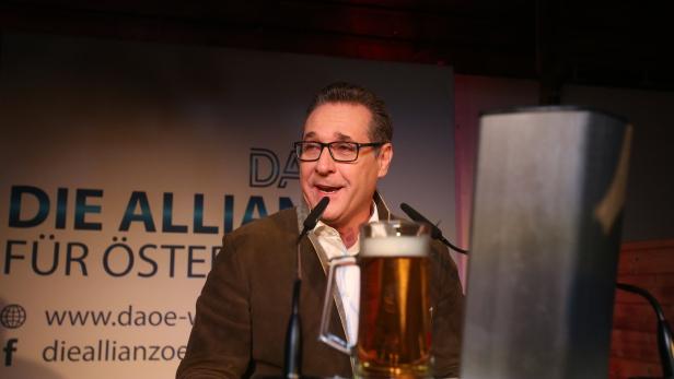 Ein Mann in Tracht spricht am Rednerpult mit einem Bierkrug davor.