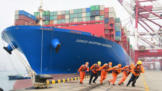 Hafen von Qingdao: Arbeiter mit Schutzmasken legen ein Containerschiff an die Leine