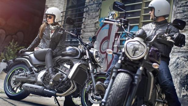 Zwei Personen sitzen auf ihren Kawasaki Vulcan Motorrädern vor einer Wand mit Graffiti.