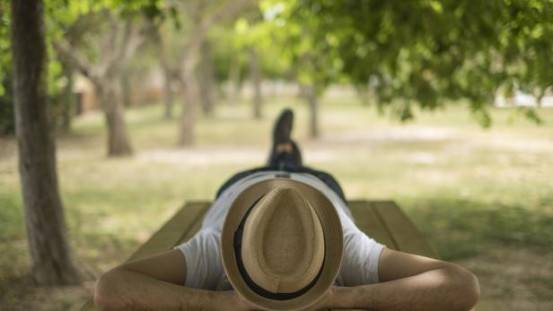 Restful boy laying down on a park wearing a hat