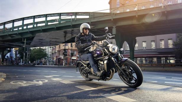 Ein Mann fährt mit einem Motorrad unter einer Brücke in einer Stadt.