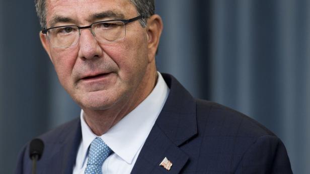 Ein Mann mit Brille und Anzug mit amerikanischer Flagge am Revers.