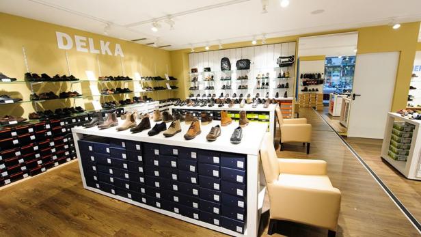 Innenansicht eines Schuhgeschäfts der Marke Delka mit Auslagen und Sitzgelegenheiten.