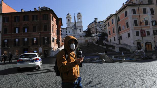A man wearing a protective face mask walks near the Rome's Spanish Steps, virtually deserted after a decree orders for the whole of Italy to be on lockdown in an unprecedented clampdown aimed at beating the coronavirus, in Rome