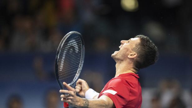 Ein Tennisspieler jubelt mit erhobenem Schläger.