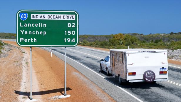 Ein Auto mit Wohnwagen fährt auf dem Indian Ocean Drive in Richtung Perth.
