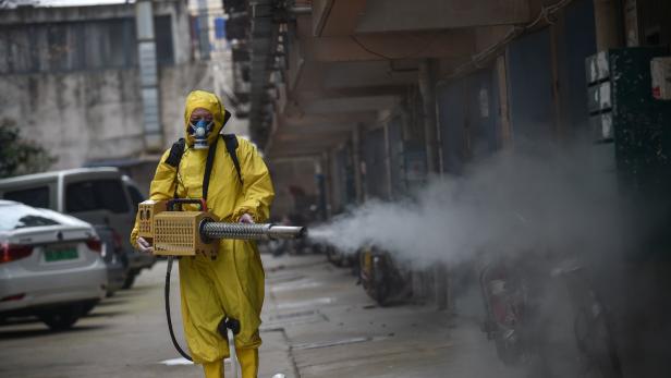 Ein medizinischer Angestellter in Wuhan sprüht Desinfektionsmittel.
