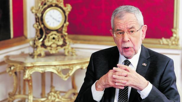 Alexander Van der Bellen vor einer goldenen Uhr.