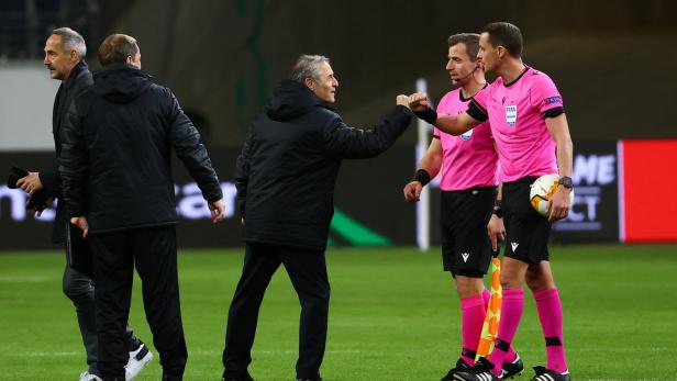 Ein Trainer gibt einem Schiedsrichter vor einem Fußballspiel ein Faustzeichen.