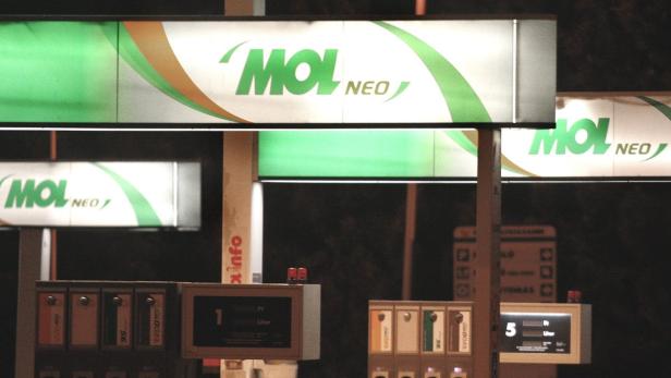 Eine Tankstelle der Marke MOL mit Preisanzeigen im Dunkeln.