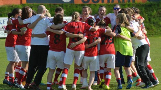 Eine Fußballmannschaft umarmt sich auf dem Spielfeld.