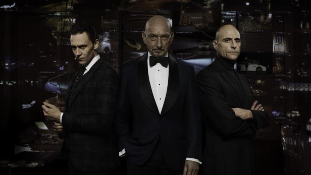 Tom Hiddleston, Ben Kingsley und Mark Strong posieren vor einer Wand mit Überwachungsbildschirmen.