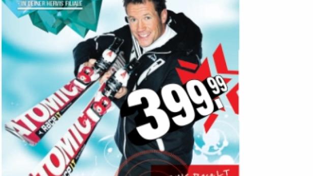 Ein Mann hält Atomic-Ski in die Kamera; Werbung für Hervis und ein Trainingscamp.