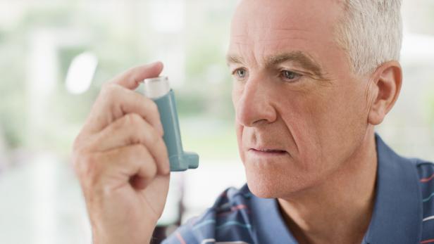 Senior man about to use asthma inhaler  