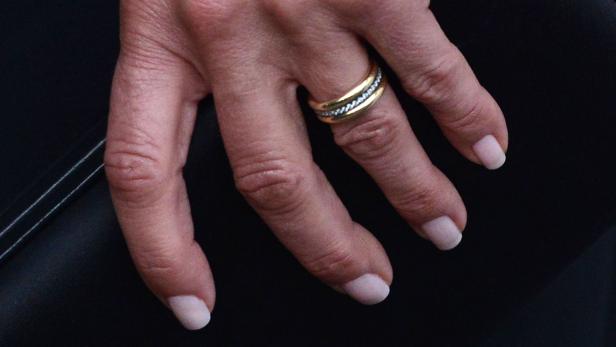 Nahaufnahme einer Hand mit goldenem Ring mit Diamanten.
