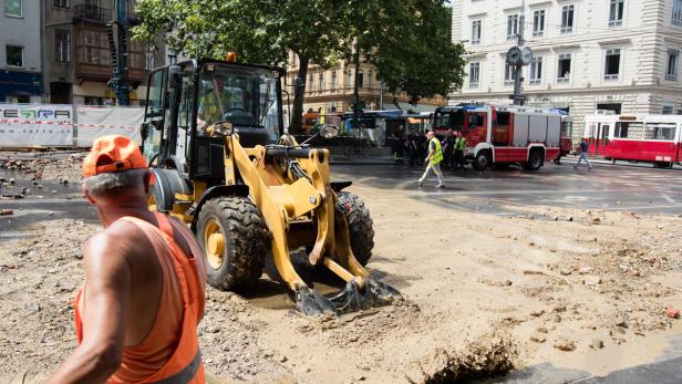 Ein Bauarbeiter steht vor einem Bagger auf einer Baustelle in der Stadt.