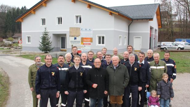 Eine Gruppe von Feuerwehrleuten posiert vor einem neuen Feuerwehrhaus.