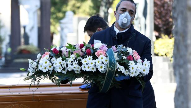 Cemetery workers and funeral agency workers in protective masks transport a coffin of a person who died from coronavirus disease (COVID-19), into a cemetery in Bergamo