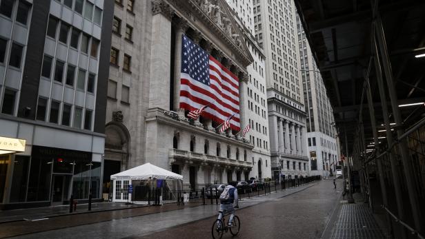Ein Radfahrer fährt vor der New Yorker Börse mit einer großen US-Flagge.
