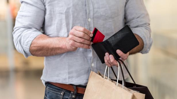 Shopping man putting credit card in his wallet