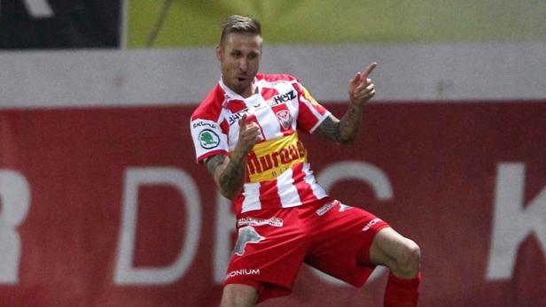Ein Fußballspieler in rot-weiß gestreifter Spielkleidung jubelt auf dem Spielfeld.