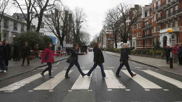 Tourists walk on a zebra crossing to recreate the Abbey Road album cover by The Beatles, outside the Abbey Road recording studios in London