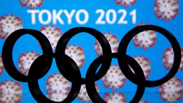 A 3D printed Olympics logo is seen in front of displayed  "Tokyo 2021" words in this illustration